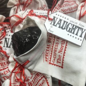 Lump of coal dark chocolate with almonds in holiday bag with tag