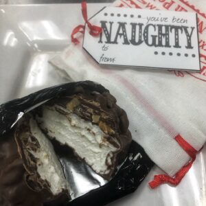 Lump of coal milk chocolate with walnuts in holiday bag with tag
